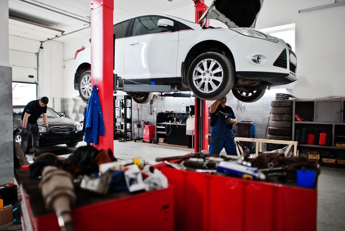 Car on a lift in a workshop with red tool trolleys